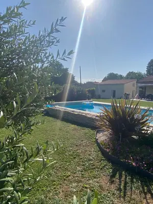 a swimming pool in a yard with the sun shining at Tiny-house chez l'habitant in Lautrec