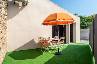 a table with an umbrella and chairs on green grass at L'appenti in Luc-sur-Orbieu