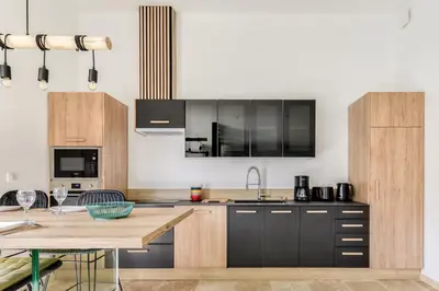 a kitchen with black cabinets and a wooden table at L'appenti in Luc-sur-Orbieu