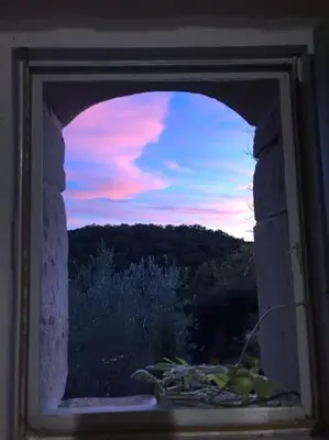 a view of a sunset through a window at Villa - Mas de campagne prestigieux- Authentic french countryhouse in dream countryside in Algans