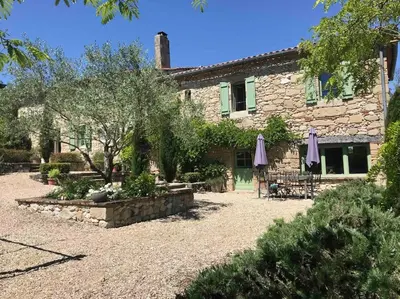 a stone house with two umbrellas in front of it at Villa - Mas de campagne prestigieux- Authentic french countryhouse in dream countryside in Algans