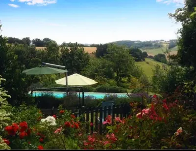 a garden with a fence and an umbrella and flowers at Villa - Mas de campagne prestigieux- Authentic french countryhouse in dream countryside in Algans