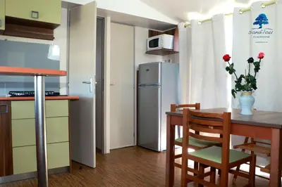a small kitchen with a table and a refrigerator at Mobilhome «Aux Portes du Soleil» in Sigean