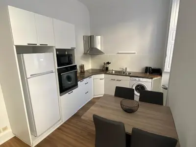 a kitchen with a table and a refrigerator and a sink at Appartement - 2 chambres - Parking voiture in Mazamet
