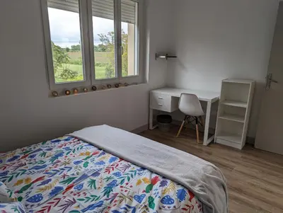 a bedroom with a bed and a desk and a window at La Fontaine in Montgaillard-Lauragais
