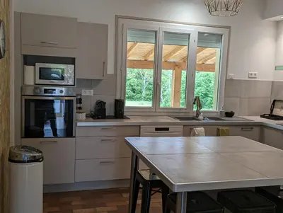 a kitchen with white cabinets and a table in it at La Fontaine in Montgaillard-Lauragais
