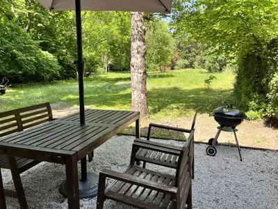 a picnic table with a bbq and two chairs and a grill at Gîte des Canelles in Villespy