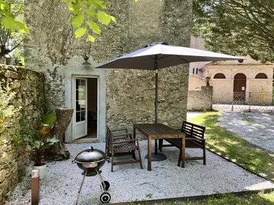 a table and chairs with an umbrella and a grill at Gîte des Canelles in Villespy