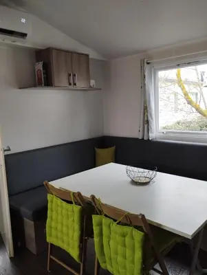 a dining room with a white table and green chairs at Mobil home in Port-la-Nouvelle