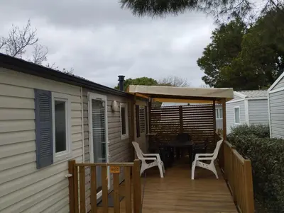 a deck with a table and chairs on a house at Mobil home in Port-la-Nouvelle