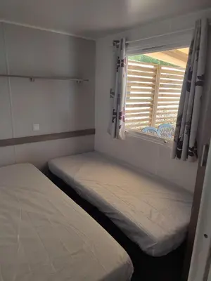 two beds in a small room with a window at Mobil home in Port-la-Nouvelle