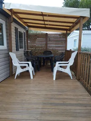 a deck with a table and chairs and an umbrella at Mobil home in Port-la-Nouvelle