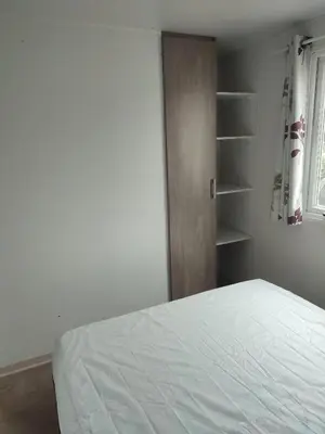 a bedroom with a white bed and a book shelf at Mobil home in Port-la-Nouvelle