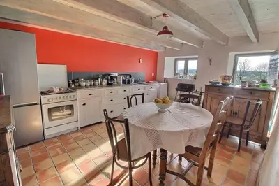 a kitchen with a table and a kitchen with red walls at Maison en pierre dans le Sidobre in Le Bez
