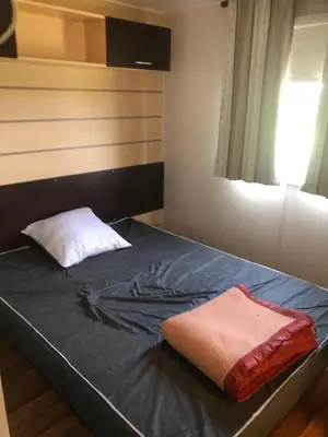 a bedroom with a bed with a pillow and a window at Mobil home 3 CH in Damiatte