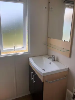 a bathroom with a sink and a mirror and a window at Mobil home 3 CH in Damiatte