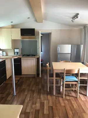 a kitchen with a wooden table and a table and chairs at Mobil home 3 CH in Damiatte