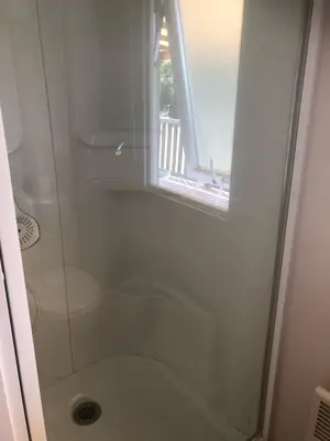 a bathroom with a shower with a toilet and a window at Mobil home 3 CH in Damiatte