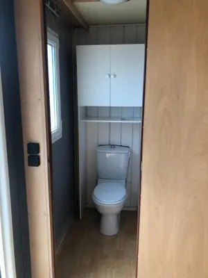 a bathroom with a white toilet in a room at Mobil home 3 CH in Damiatte