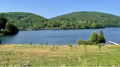 a large lake with a group of people in a field at Chalet dans le parc d'un manoir du XIXème in Anglès