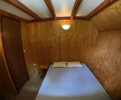 a small room with a bed in a wooden room at Chalet dans le parc d'un manoir du XIXème in Anglès