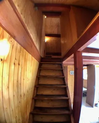 a staircase in a cabin with wooden walls at Chalet dans le parc d'un manoir du XIXème in Anglès