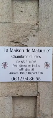 a sign on the side of a brick wall at La maison de Malaurie in Gruissan