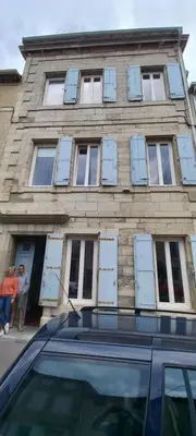 a building with blue shuttered windows and a car in front at La maison de Malaurie in Gruissan
