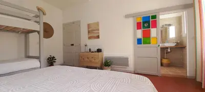a bedroom with a bed and a bathroom with a sink at La maison de Malaurie in Gruissan
