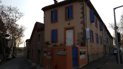 a building with blue windows on a street at Millot Conilhac in Conilhac-Corbières