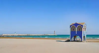 a blue building on a beach with the ocean at Mobil Home de Marine in Port-la-Nouvelle