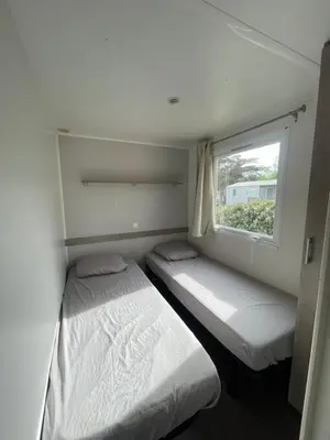 two beds in a small room with a window at Mobil Home de Marine in Port-la-Nouvelle