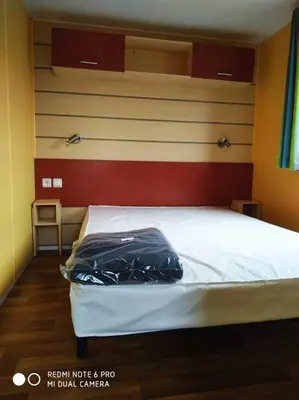 a bedroom with a white bed with a red and yellow wall at Mobil home au bord du lac in Nages