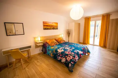 a bedroom with a bed and a table and a desk at Gîte du Montagut in Thézan-des-Corbières