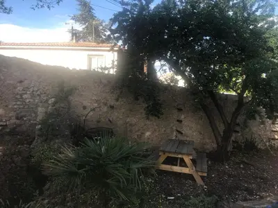 a wooden bench next to a stone wall with a tree at Douceur occitane in Saint-Chinian