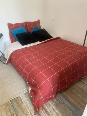 a bed with a red blanket and pillows on it at Au pied du centre ville - Mignon petit studio climatisé in Narbonne