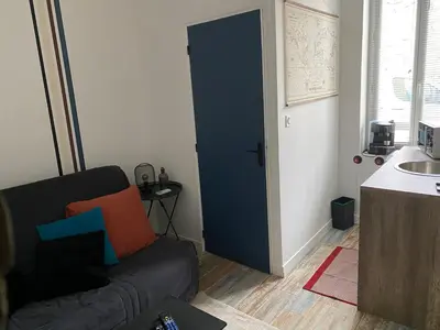 a living room with a black couch and a sink at Au pied du centre ville - Mignon petit studio climatisé in Narbonne