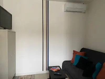 a living room with a couch and a tv at Au pied du centre ville - Mignon petit studio climatisé in Narbonne