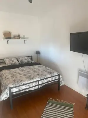a bedroom with a bed and a flat screen tv at Proche des plages - Beau T2 climatisé in Narbonne