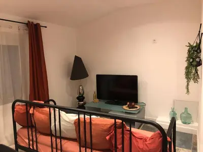 a living room with a couch and a tv and a table at Charmant T2 climatisé - Près des plages in Narbonne