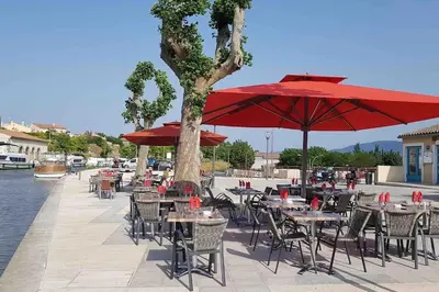 a group of tables and chairs with red umbrellas at La Casa de Gaëlle 2 in Trèbes