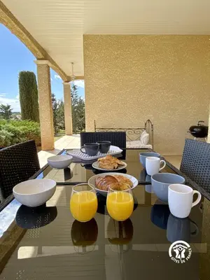 a glass table with food and orange juice on it at Les iris in Castelnau-dʼAude