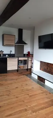 a kitchen with wooden floors and a flat screen tv at demeure de charme in Mazères