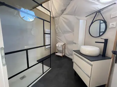 a bathroom with a shower and a sink in a tent at Bulle d'Amour - Dôme avec spa privatif dans les Corbières in Durban-Corbières