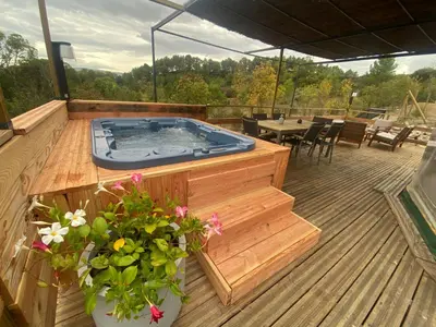a hot tub on a wooden deck with plants at Bulle d'Amour - Dôme avec spa privatif dans les Corbières in Durban-Corbières
