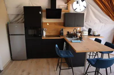 a kitchen with a wooden table and a refrigerator at Bulle d'Amour - Dôme avec spa privatif dans les Corbières in Durban-Corbières