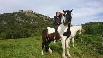a woman sitting on a horse in a field at Gîtes à la Ferme - Hautes-Corbières in Termes