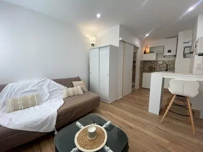 a living room with a couch and a table and a kitchen at Mon petit studio à la mer in Gruissan