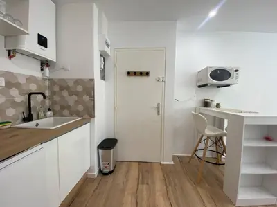 a small white kitchen with a sink and a door at Mon petit studio à la mer in Gruissan