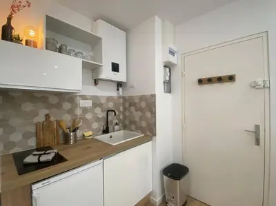 a kitchen with white cabinets and a sink at Mon petit studio à la mer in Gruissan